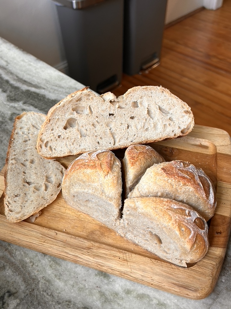 Slices of fresh sourdough bread showing a light, airy crumb and golden crust. Sliced Sourdough Bread Loaf on a Cutting Board