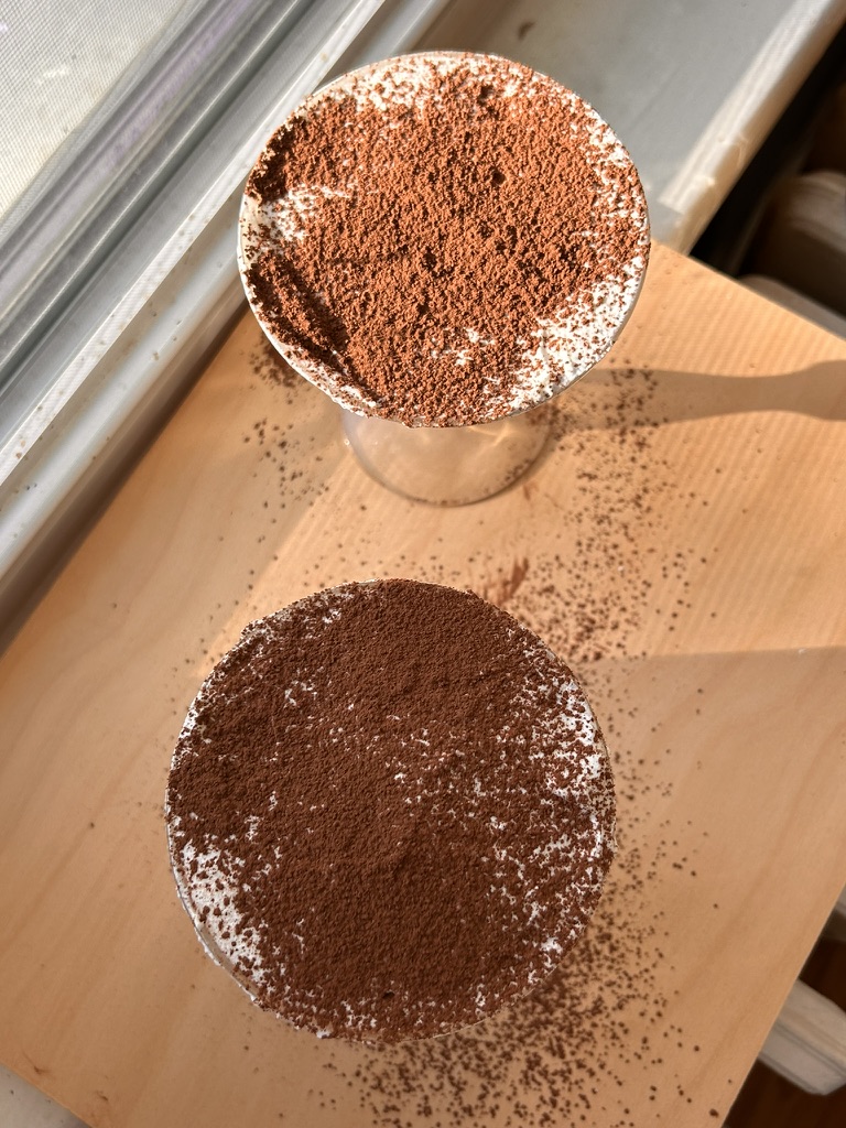 Close-up of individual tiramisu cups dusted with cocoa powder, capturing the layered creamy and coffee-soaked goodness of a classic Italian dessert.