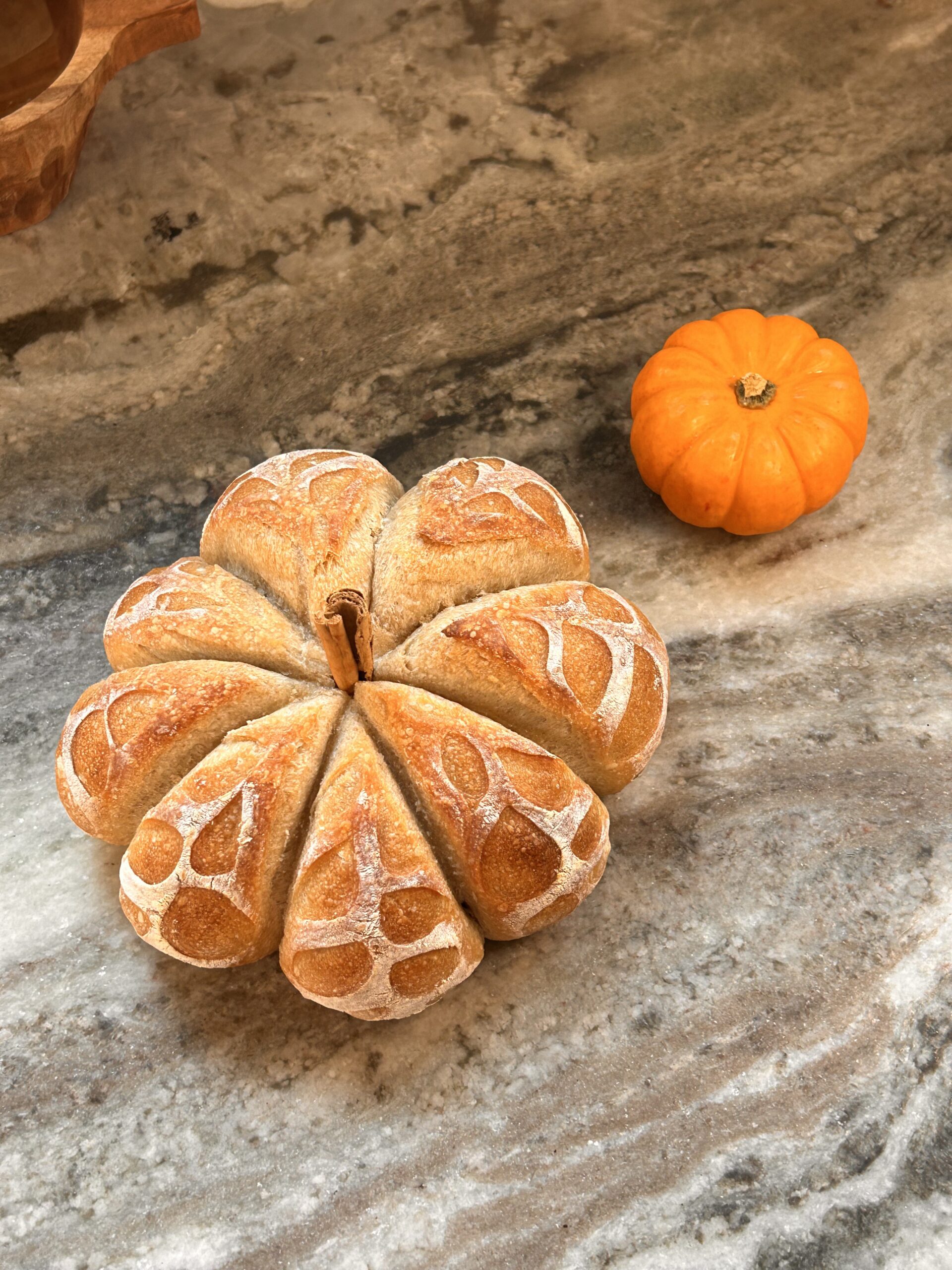 Perfect Pumpkin-Shaped Bread for Fall. Whole pumpkin-shaped bread loaf with a golden crust and intricate score marks.