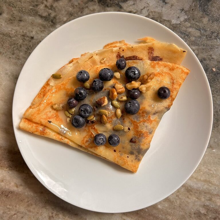 Sourdough discard crepe filled with dark chocolate, bananas, pumpkin seeds, walnut seeds, flax, chia, topped with blueberries and maple whipped honey. A homemade sweet and savory breakfast crepe for Iski's Bakehouse