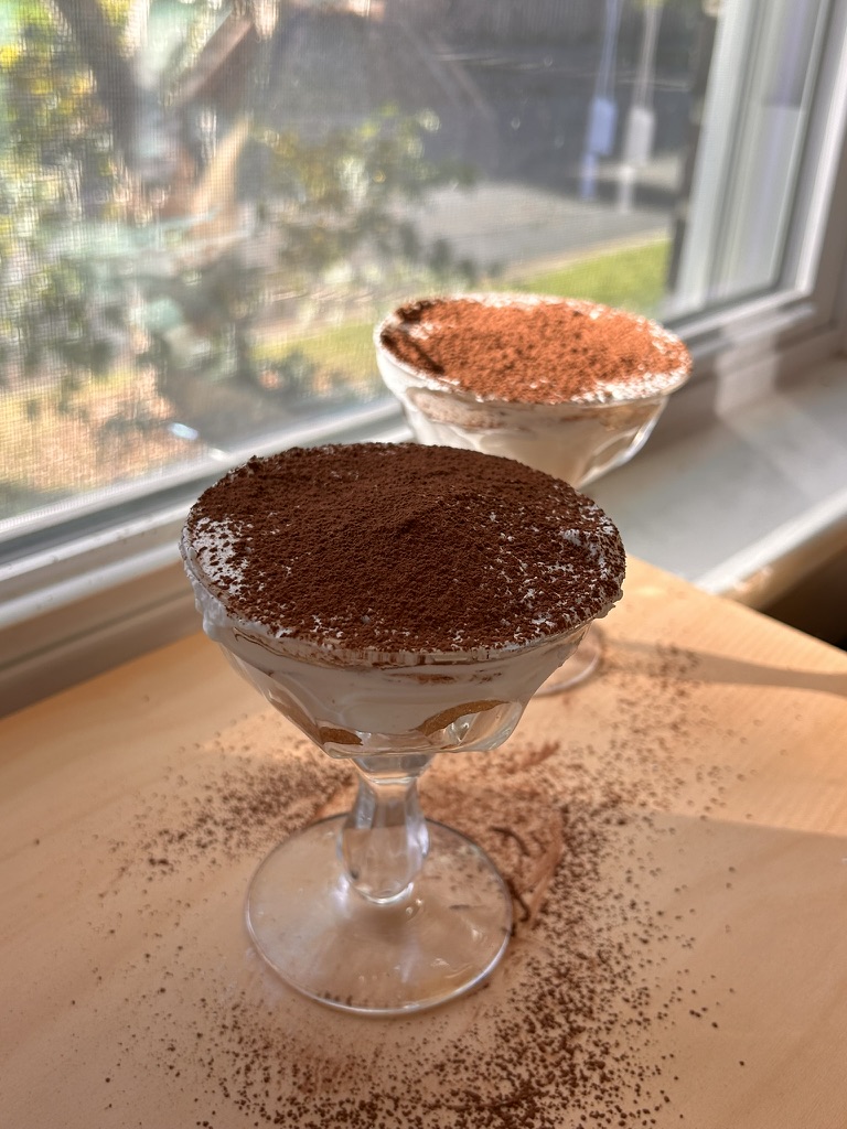 Close-up of individual tiramisu cups dusted with cocoa powder, capturing the layered creamy and coffee-soaked goodness of a classic Italian dessert.