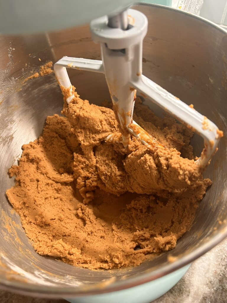 Thick ginger cookie dough in a stand mixer with a paddle attachment, ready to be scooped and baked.