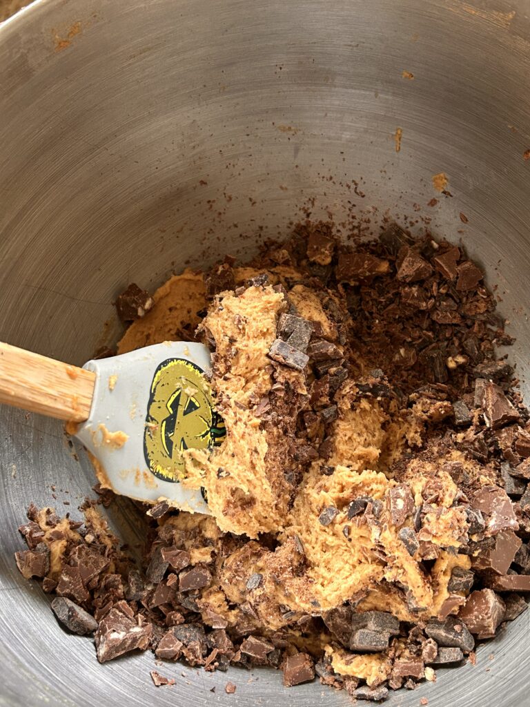 Mixing bowl filled with brown butter miso cookie dough and chunks of dark chocolate, ready for scooping.